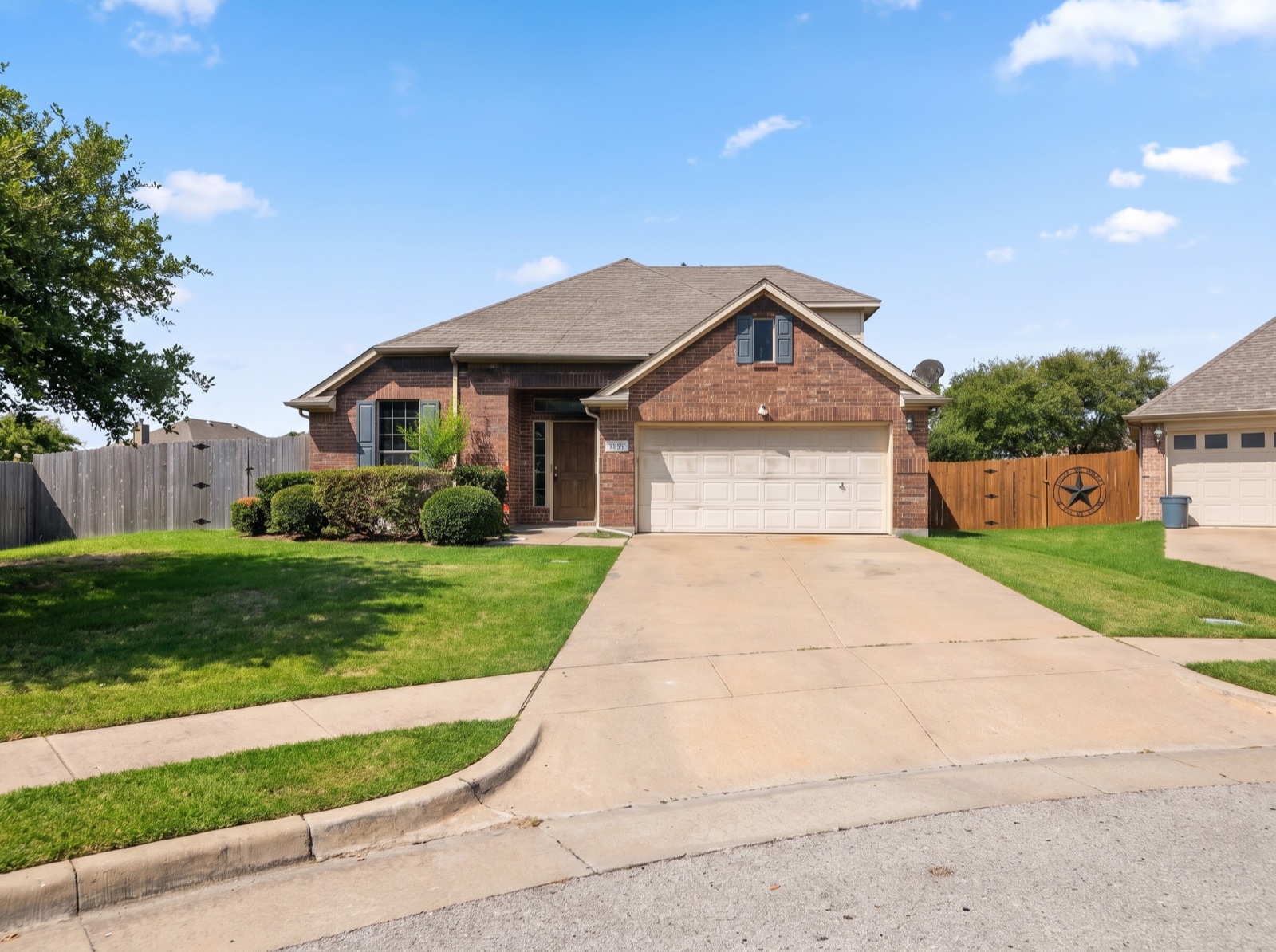 Red-brick single-family home with a wide driveway on a sunny Texas cul-de-sac